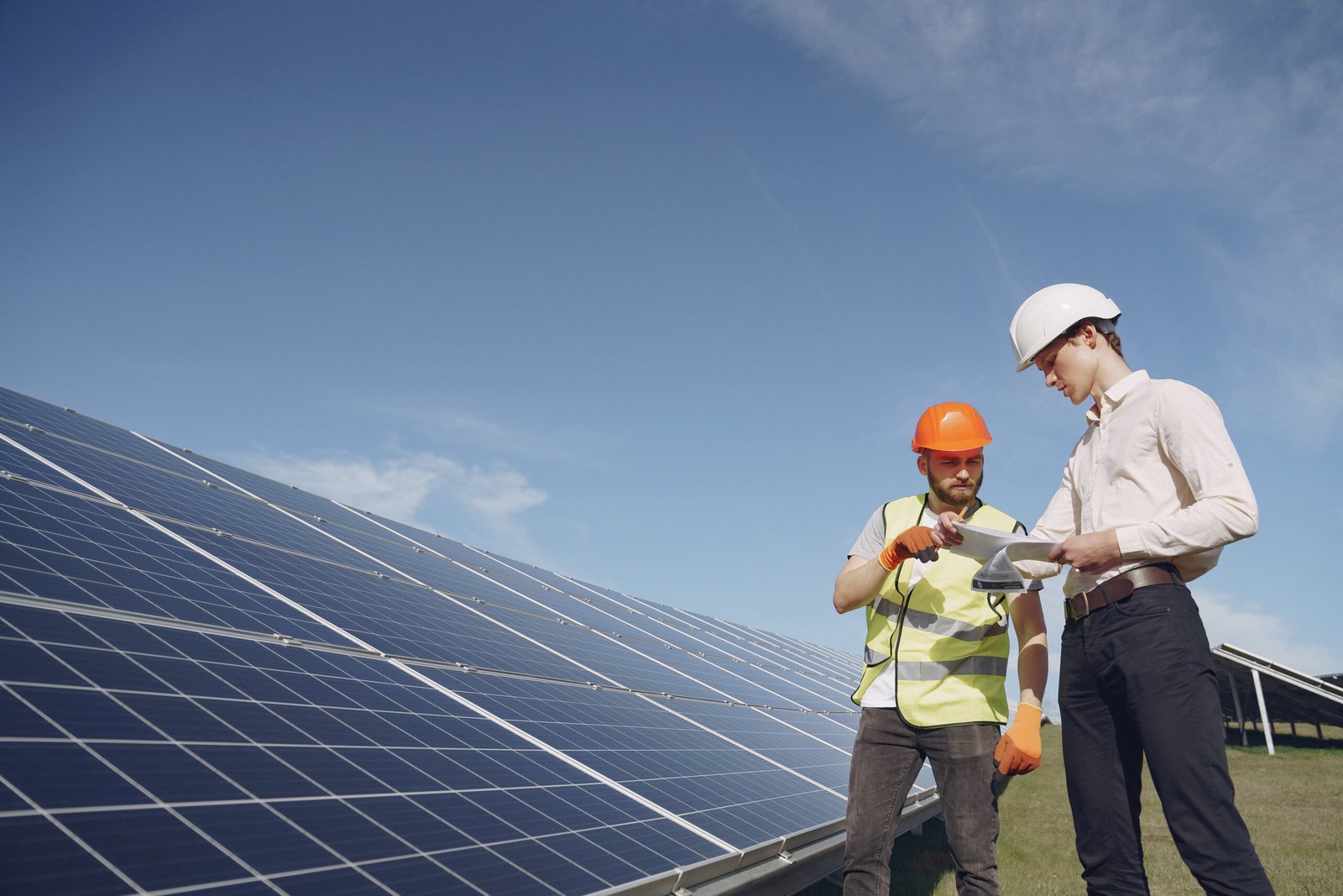 Businessman and worker near solar energy batteries. Business client showing photovoltaic detail to foreman. Two men making deal.